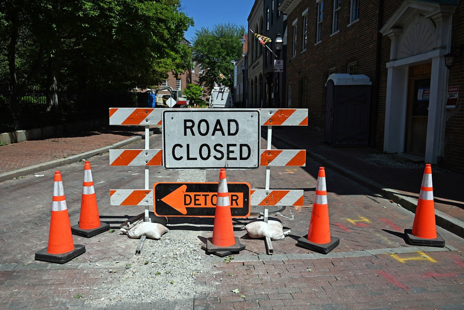 A road closed sign surrounded by orange traffic cones